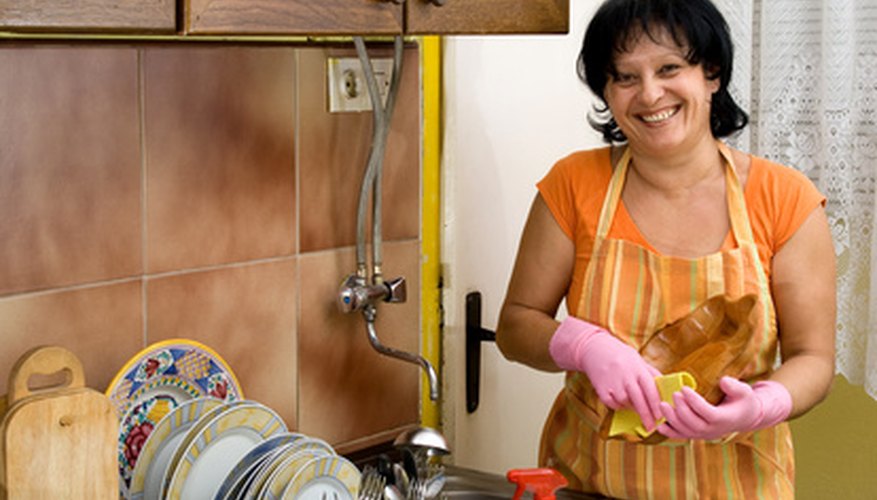 Photo Credit: woman washing dishes in the kitchen image by dinostock from <a href='http://www.fotolia.com'>Fotolia.com</a> Always wash antique dishes by hand.