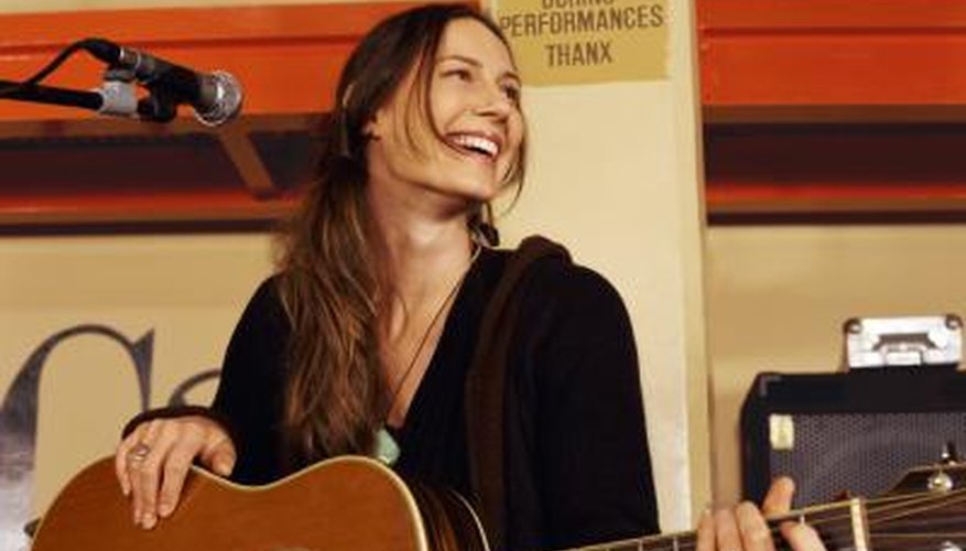 Photo Credit: Digital Vision./Digital Vision/Getty Images Woman with guitar on stage
