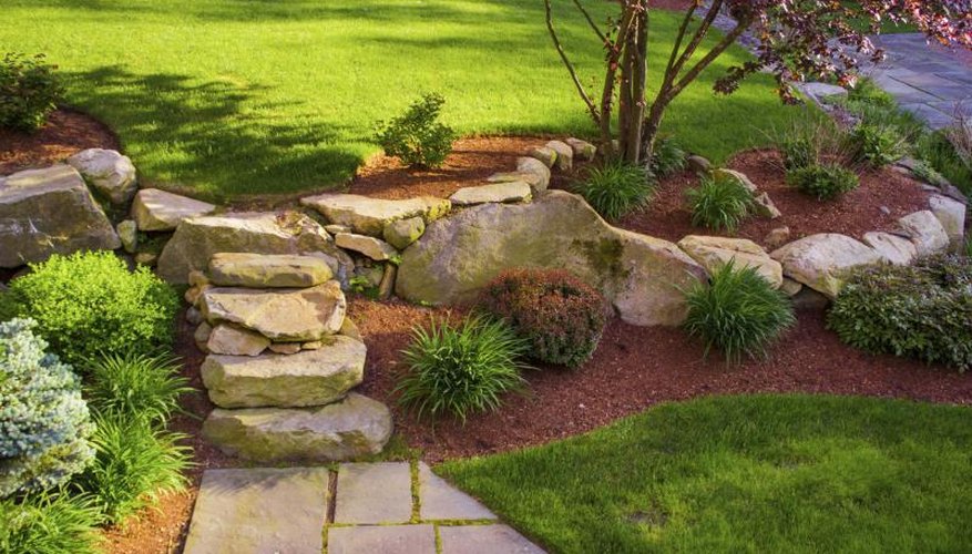 A rock garden with mulch highlights a slope in the front yard. A rock garden with mulch highlights a slope in the front yard.