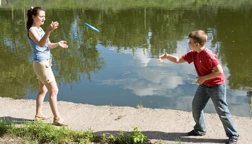 Kids playing frisbee outdoors next to lake. Kids playing frisbee outdoors next to lake.