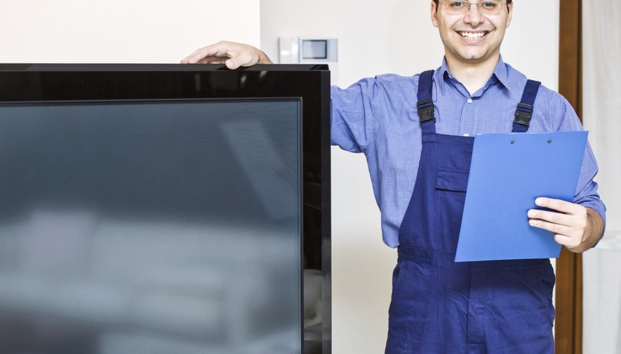 A smiling TV maintenance man stands next to a television. A smiling TV maintenance man stands next to a television.