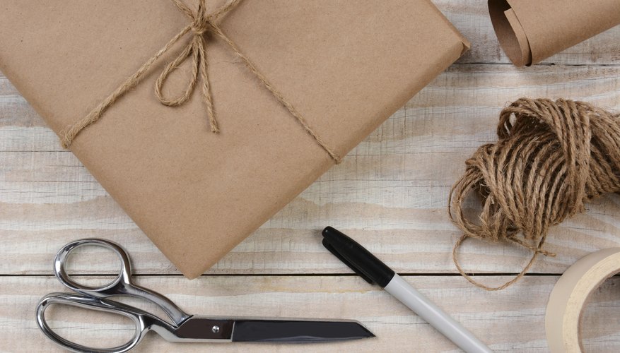 A gift wrapped in brown butcher paper sitting on a table with scissors, tape, string and a marker. A gift wrapped in brown butcher paper sitting on a table with scissors, tape, string and a marker.