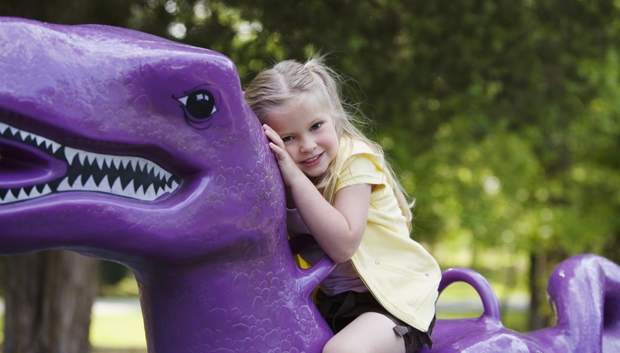 A girl sits atop a spring rider dinosaur. A girl sits atop a spring rider dinosaur.