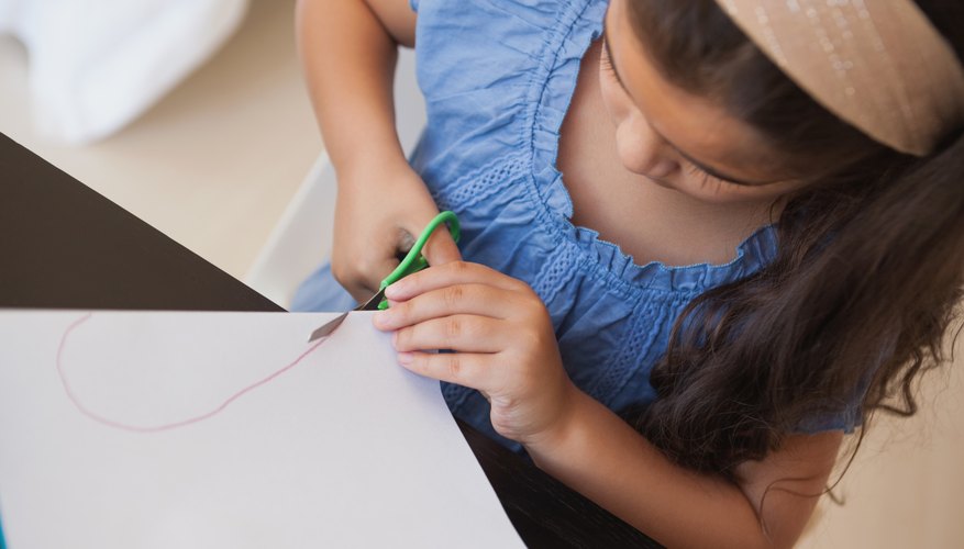 Young child using scissors to cut paper Young child using scissors to cut paper