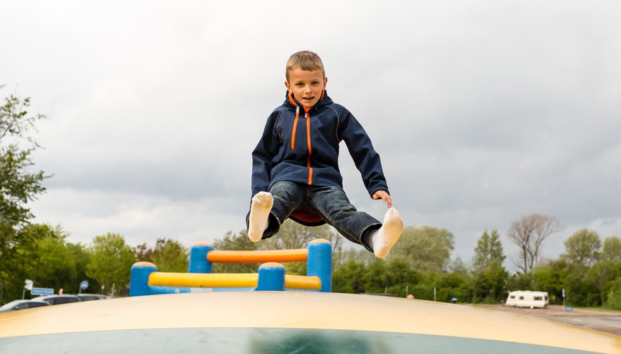 A young boy is bouncing on a trampoline. A young boy is bouncing on a trampoline.