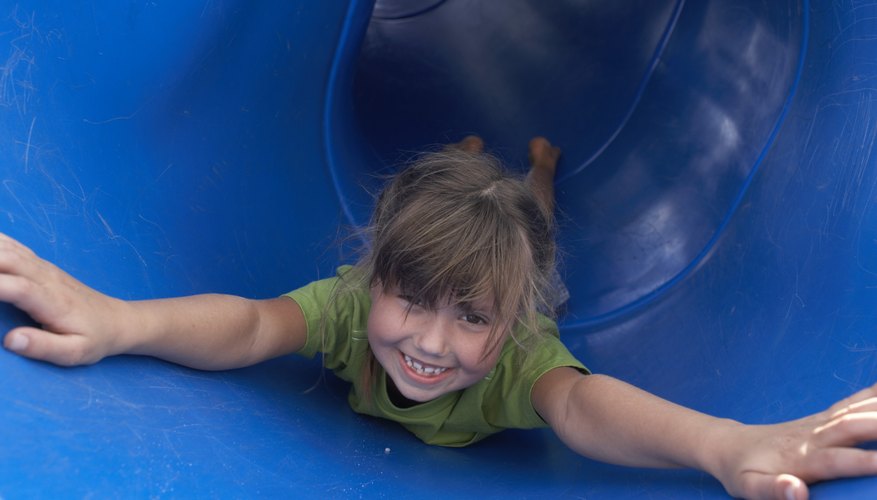 A girl happily slides down a plastic tube slide. A girl happily slides down a plastic tube slide.