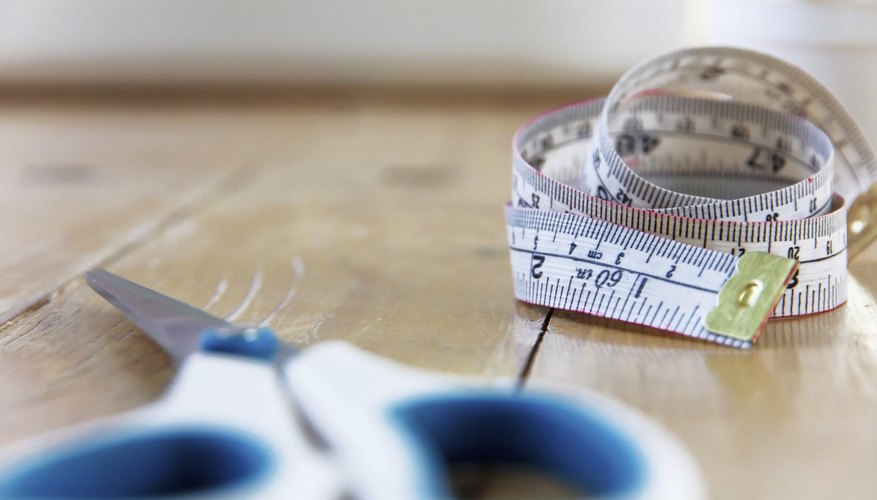 A close-up of a tape measure on a table with a pair of scissors. A close-up of a tape measure on a table with a pair of scissors.