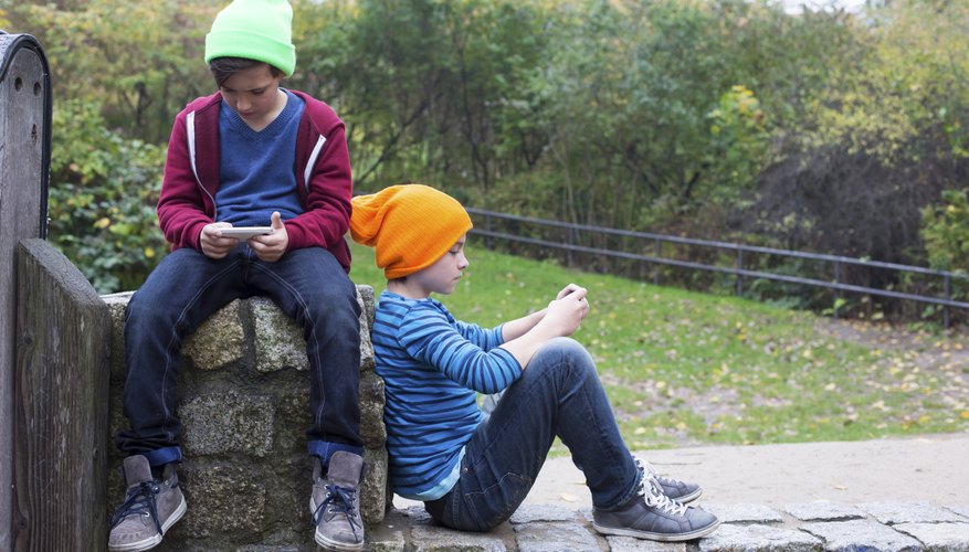 Two boys sitting on a stone wall using smart phones. Two boys sitting on a stone wall using smart phones.