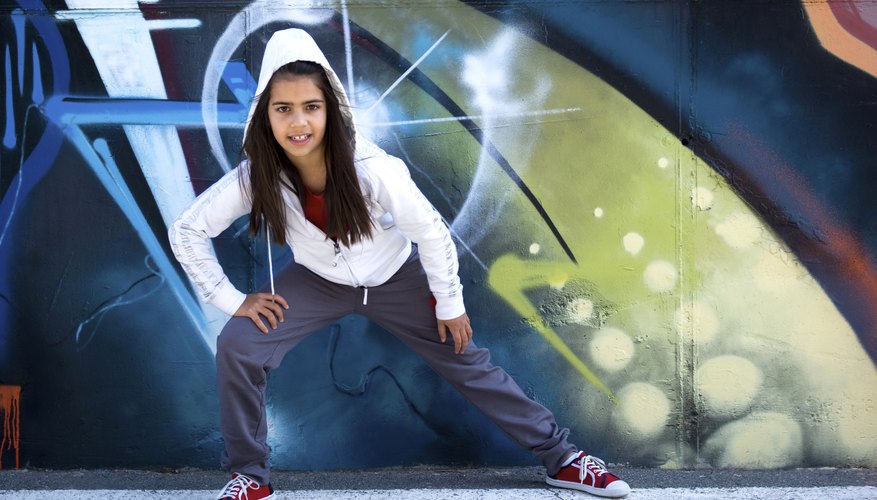 Young girl dancing in front of a graffiti wall. Young girl dancing in front of a graffiti wall.