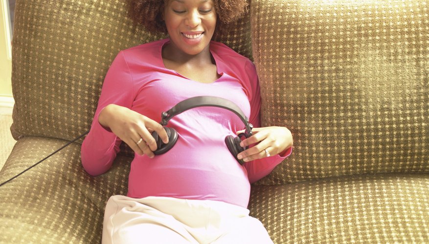 Pregnant woman holding headphones to belly. Pregnant woman holding headphones to belly.