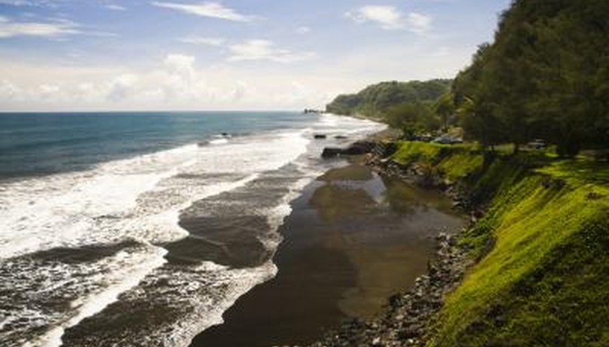 Tides roll into a beach with lush cliffs. Tides roll into a beach with lush cliffs.