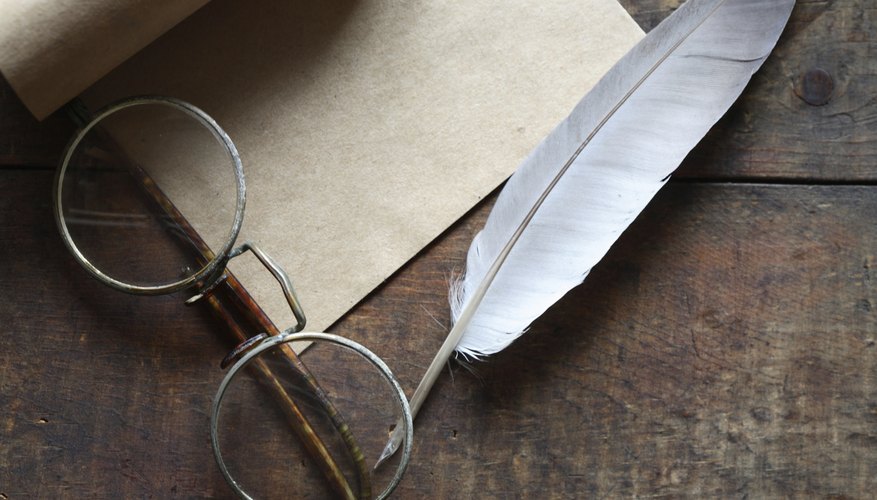 An overhead view of a quill, scroll and eyeglasses on a table. An overhead view of a quill, scroll and eyeglasses on a table.