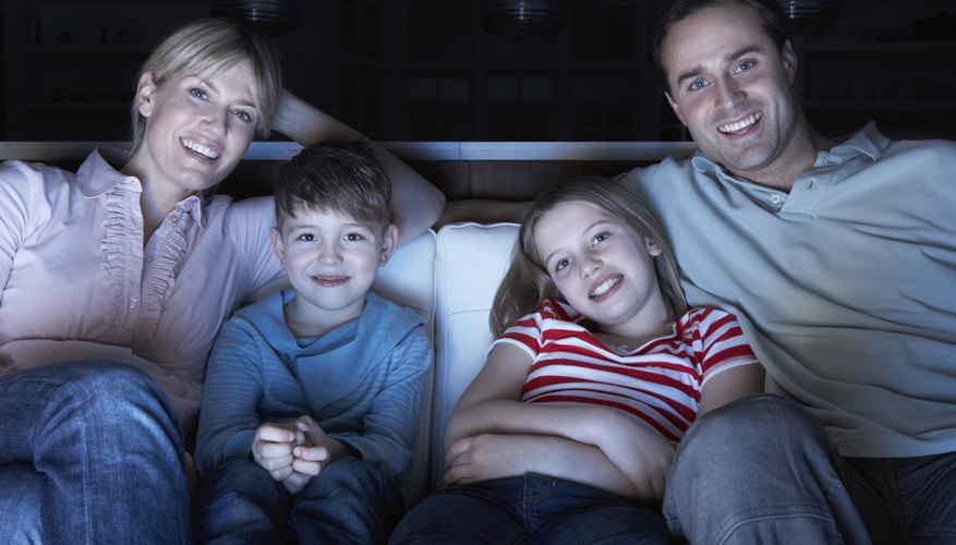 A family sitting on a sofa watching a DVD. A family sitting on a sofa watching a DVD.