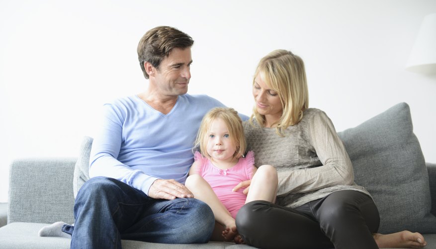 Smiling parents sitting on couch with their daughter. Smiling parents sitting on couch with their daughter.