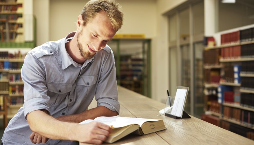 Photo Credit: Robert Kneschke/iStock/Getty Images A man reads a page in a book at the library.
