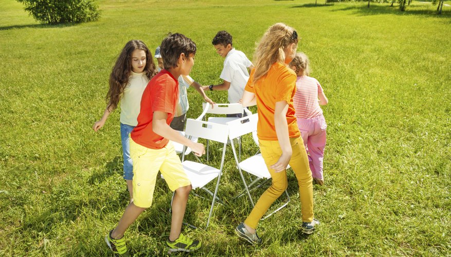 A group of children play musical chairs in the park. A group of children play musical chairs in the park.