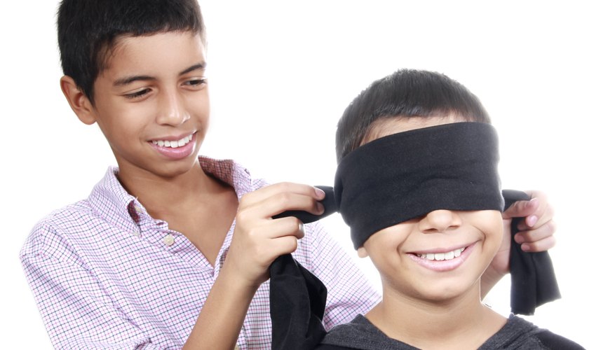 A boy ties a blindfold over the eyes of a yonger boy. A boy ties a blindfold over the eyes of a yonger boy.