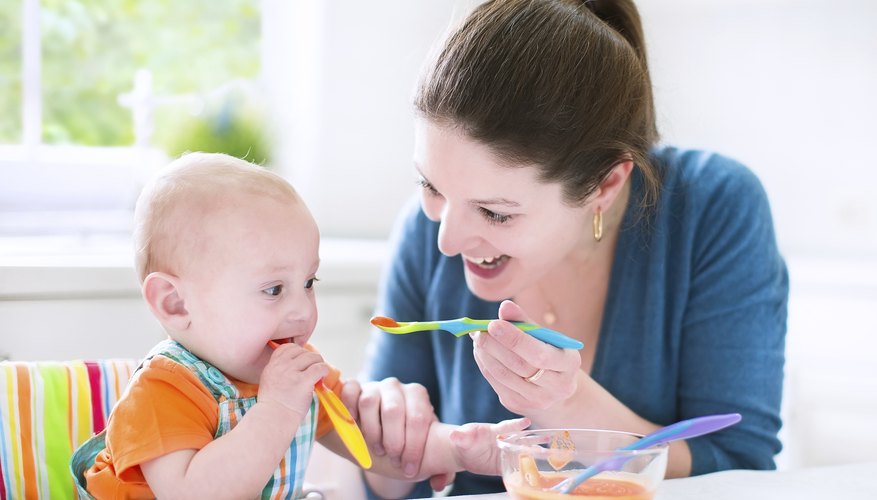 Mother feeding her baby with spoonfuls of vegetables. Mother feeding her baby with spoonfuls of vegetables.