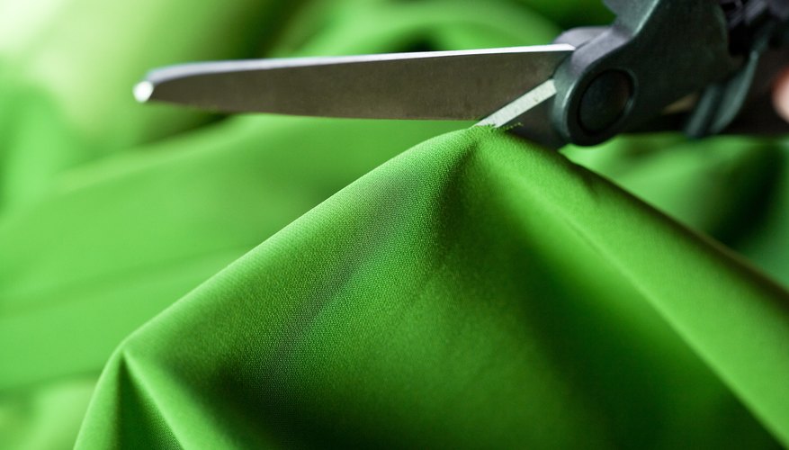 Scissors cutting green fabric Scissors cutting green fabric