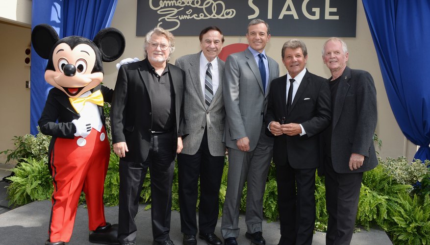 The CEO of the Disney Company posing with team members and Mickey Mouse at an event. The CEO of the Disney Company posing with team members and Mickey Mouse at an event.