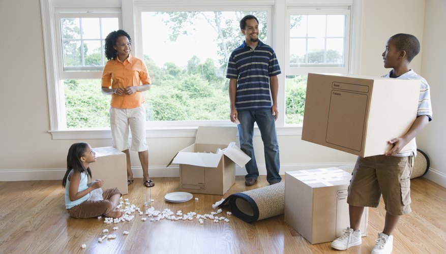 A family is holding moving boxes.