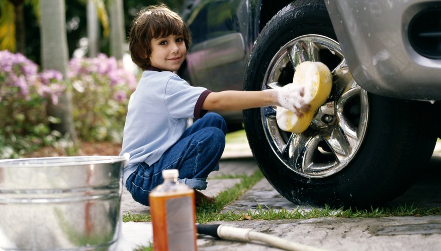 Child washing tires of car. Child washing tires of car.