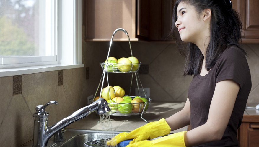 Teenager looking out the window while doing the dishes at kitchen sink. Teenager looking out the window while doing the dishes at kitchen sink.