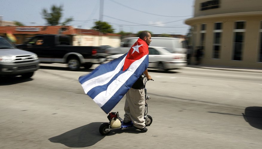 Photo Credit: Chip Somodevilla/Getty Images News/Getty Images Cuban fan riding motorized scooter
