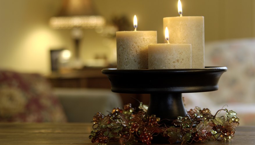 Three lit candles on a pedastal holder on a living room coffee table. Three lit candles on a pedastal holder on a living room coffee table.