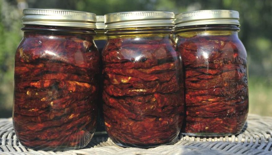Quart jars of sun-dried tomatoes on a sunny table outside. Quart jars of sun-dried tomatoes on a sunny table outside.