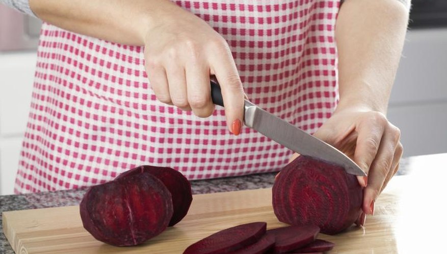A woman slicing a beet in the kitchen. A woman slicing a beet in the kitchen.
