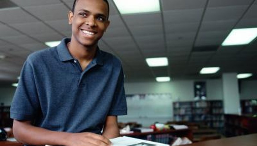 A young man browses through a book at the library. A young man browses through a book at the library.