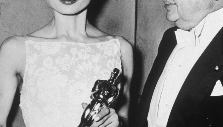 Audrey Hepburn wore a lacy white cocktail-length gown to accept her 1954 Oscar. Audrey Hepburn wore a lacy white cocktail-length gown to accept her 1954 Oscar.