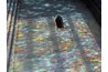 Stained glass windows paint a rainbow of colors on the opposite wall.