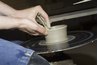 A ceramicist works with earthenware clay on a wheel in a similar fashion.
