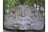 Life-size, three-dimensional carving with central figure.