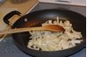 A pan transfers heat from a stove top to onions.