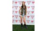 Actress Troian Bellisaio layers cutoffs with an army vest and several accessories with her rugged motorcycle boots.