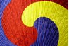 Red, blue, and yellow waves on a traditional Sam Taeguk fan.