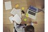 An overhead view of a woman doing accounting at home at the table.