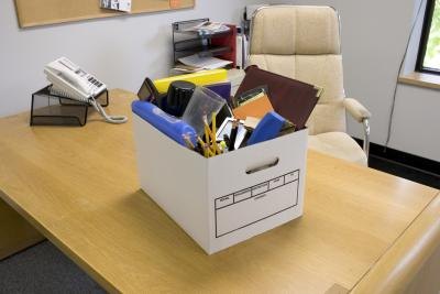 Box with office belongings on desk, symbol of unemployment.