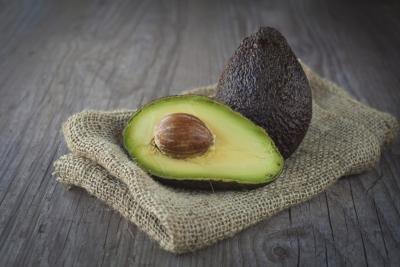 A halved avocado on a wood table. A halved avocado on a wood table.