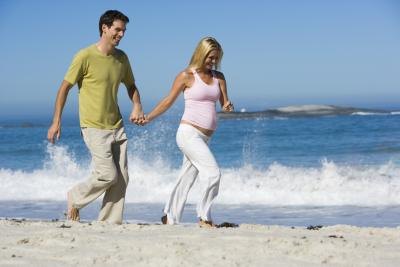 pregnant couple jogging on beach