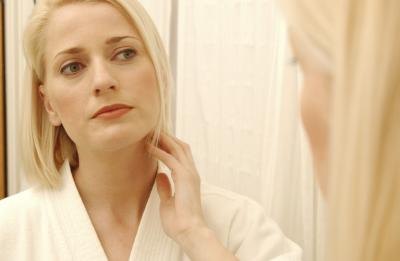 Woman looking at skin in mirror