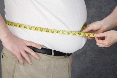 Overweight man having his midsection measured Overweight man having his midsection measured