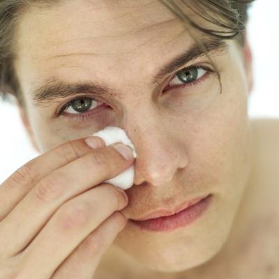 A man rubs a cottonball over his face.