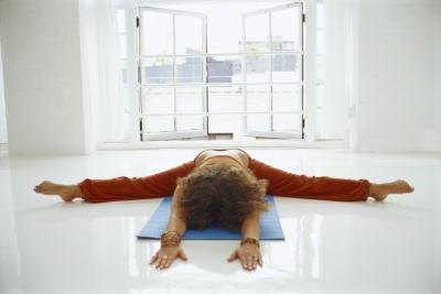 A woman does tortoise pose on a mat.