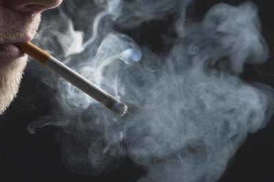 A man smokes a cigarette, smoking can lead to the swallowing of air.