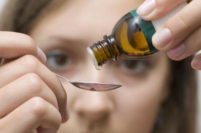 Pouring liquid oil into spoon.