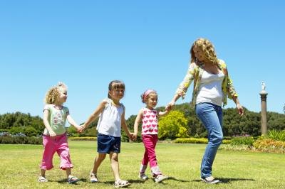 A nanny takes three girls to the park.
